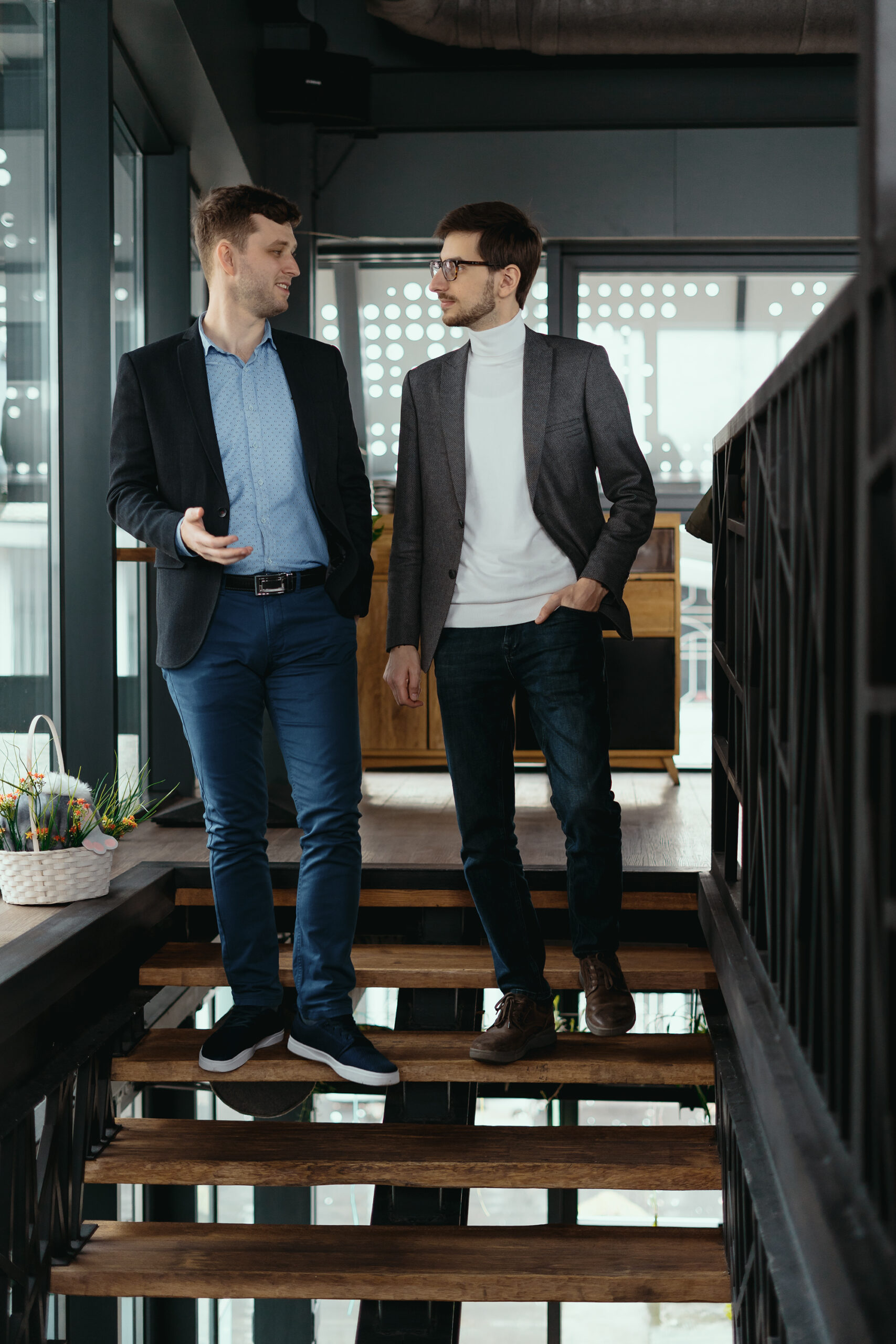 Two men walking down stairs chatting indoors
